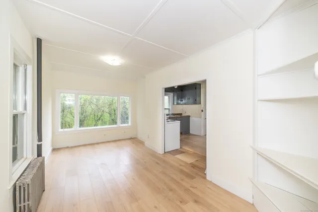 a view of empty room with wooden floor and window