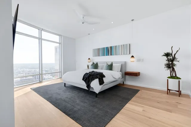 a bedroom with a bed lamp and a large window with wooden floor