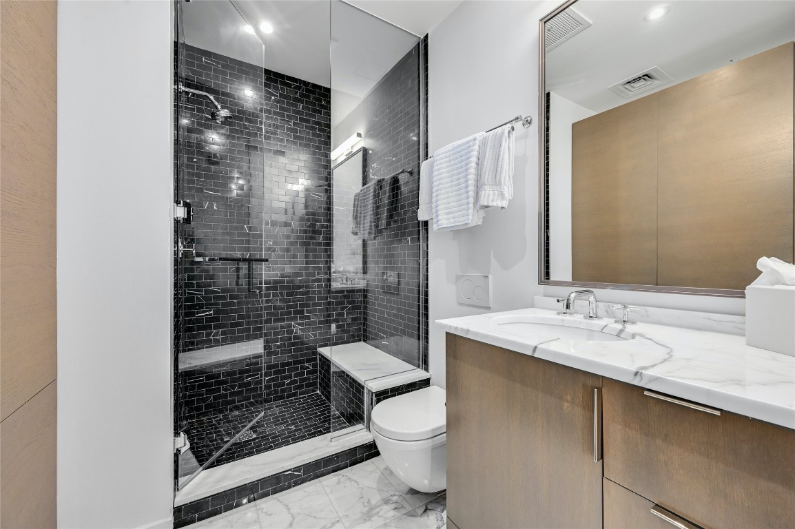 200 Congress Avenue, Unit 32SE Austin, TX 78701 - Photo 20 of 40 a bathroom with a granite countertop sink a toilet a mirror and shower