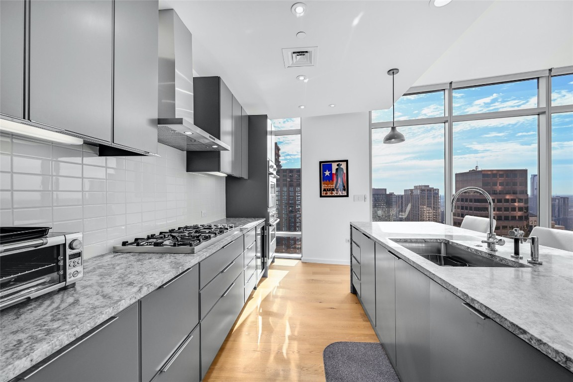 200 Congress Avenue, Unit 32SE Austin, TX 78701 - Photo 8 of 40 a kitchen with stainless steel appliances granite countertop a sink a stove and a wooden cabinets