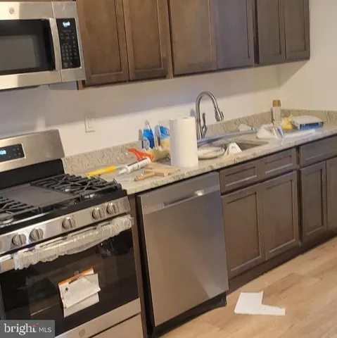 a kitchen with granite countertop a sink stainless steel appliances and cabinets