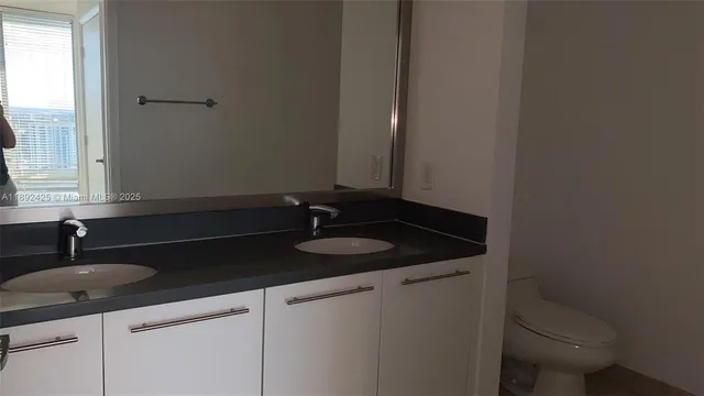 a bathroom with a granite countertop sink a toilet and a mirror