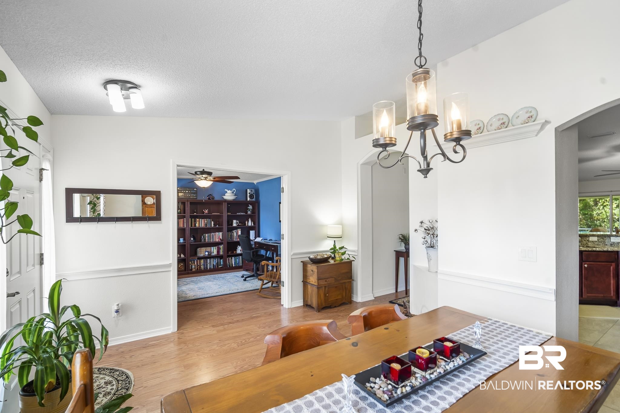 Dining room featuring arched walkways, light wood finished floors, ceiling fan, a chandelier, and a textured ceiling