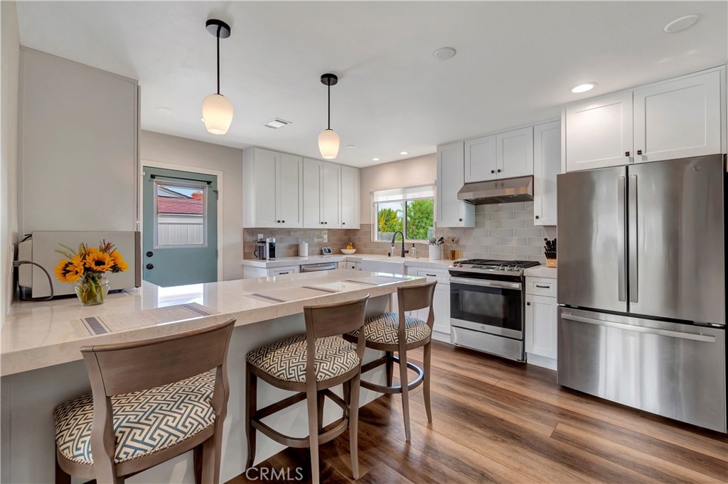 16243 Summershade Drive La Mirada, CA 90638 - Photo 11 of 34 a kitchen with a refrigerator a stove a sink and a dining table with wooden floor