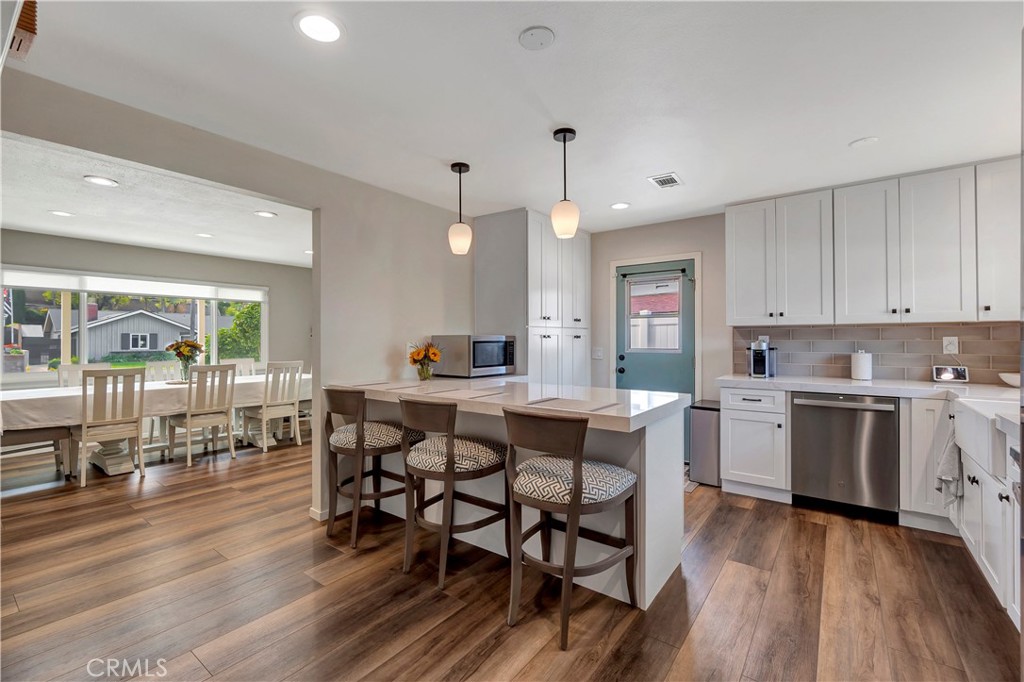 16243 Summershade Drive La Mirada, CA 90638 - Photo 10 of 34 a kitchen with stainless steel appliances granite countertop a stove a sink dishwasher a dining table and chairs with wooden floor
