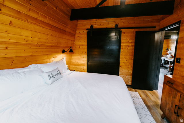 1413 Basel Drive Midway, UT 84049 - Photo 82 of 137 Bedroom with wood walls, ceiling fan, light wood-type flooring, a barn door, and a wood ceiling with exposed beams