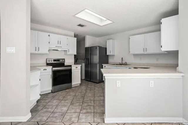 a kitchen with a refrigerator a stove top oven and cabinets