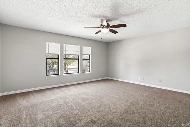 an empty room with windows and ceiling fan