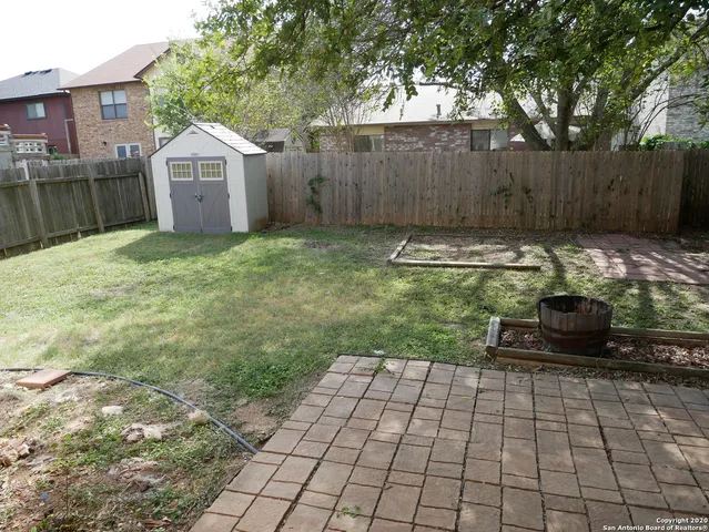 a view of a backyard with large trees and wooden fence
