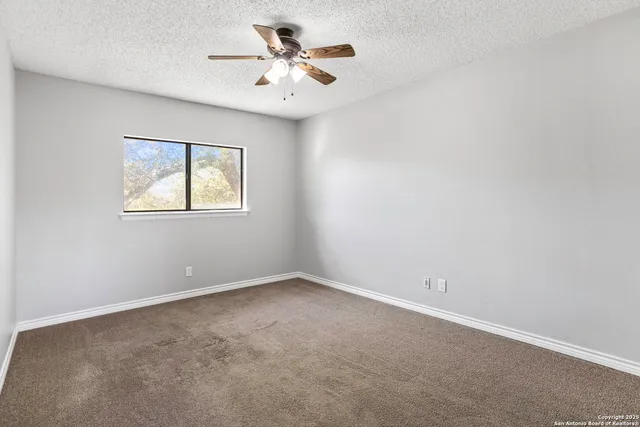 an empty room with a window and a fan