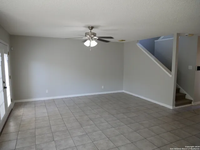 an empty room with a ceiling fan and carpet