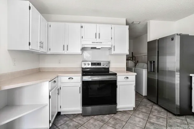 a kitchen with stainless steel appliances granite countertop a refrigerator a stove and white cabinets
