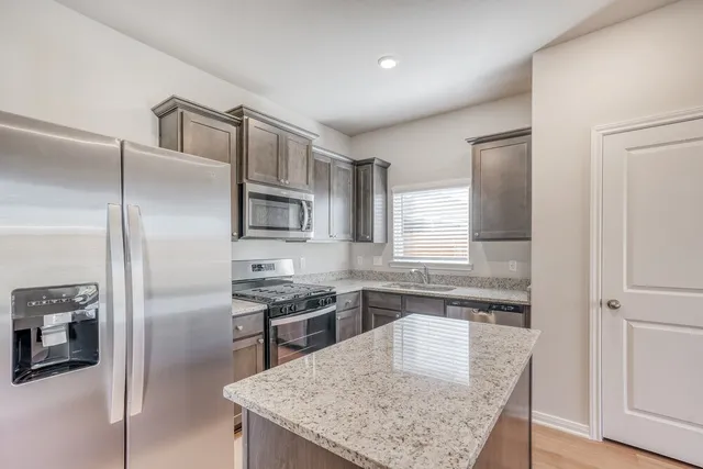 a kitchen with stainless steel appliances granite countertop a refrigerator a stove and a sink