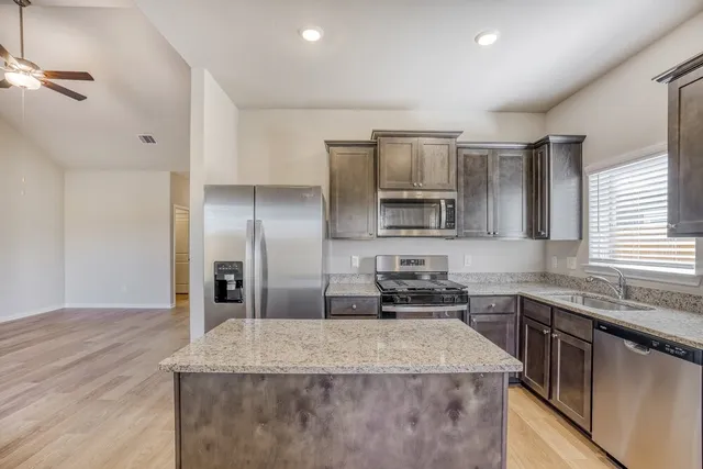 a kitchen with stainless steel appliances granite countertop a sink stove and refrigerator