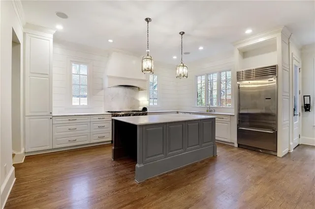 a kitchen with stainless steel appliances granite countertop a sink a stove a refrigerator and a wooden floor