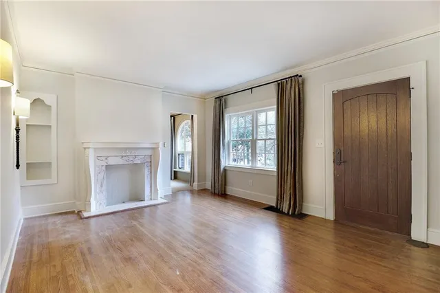 an empty room with wooden floor fireplace and windows