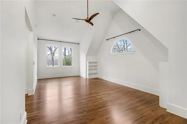 an empty room with wooden floor chandelier and windows