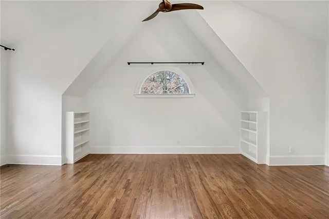 an empty room with wooden floor cabinet and windows