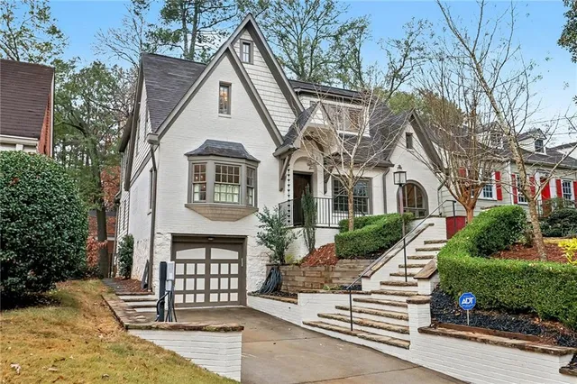 a view of a white house with large windows and a small yard