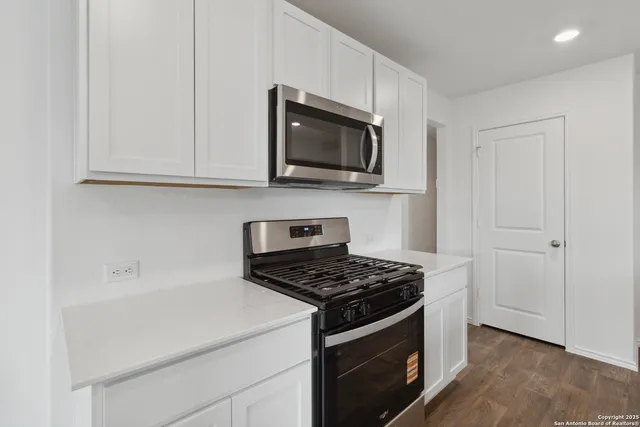 a kitchen with white cabinets and black appliances