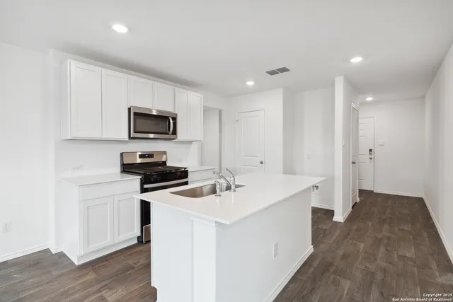 a kitchen with a sink a counter top space stainless steel appliances and cabinets