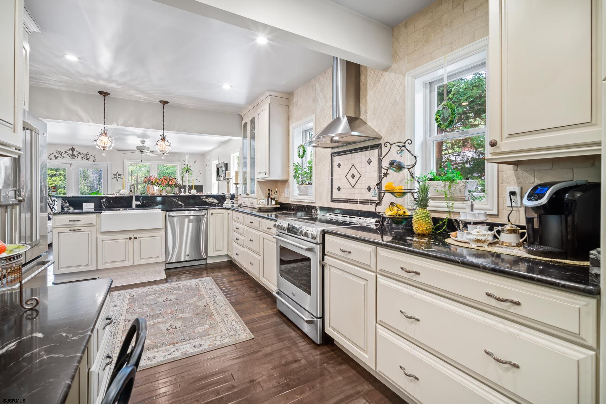 4646 Riverside Drive Sweetwater, NJ 08037 - Photo 37 of 55 a white kitchen with stainless steel appliances granite countertop a stove a sink dishwasher and white cabinets with wooden floor