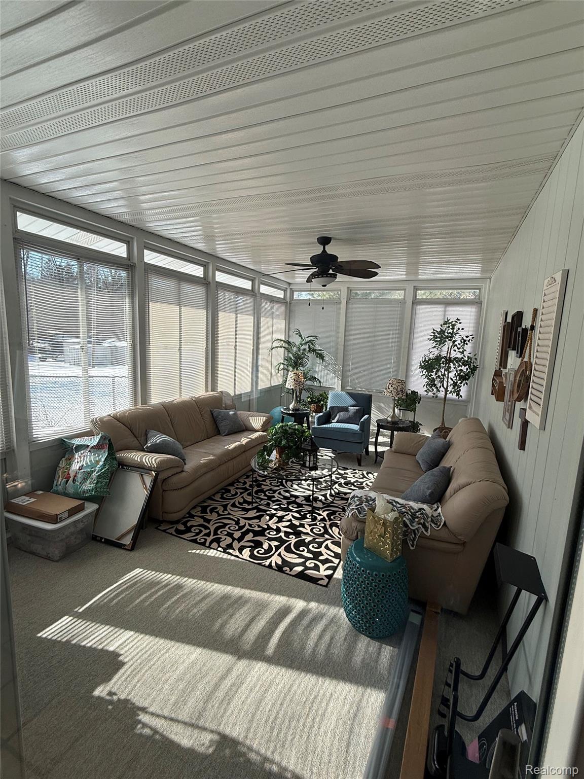 3668 East Allen Road Howell, MI 48855 - Photo 11 of 18 Sunroom featuring extensive window-lined walls, a white slatted ceiling with integrated ventilation, and a ceiling fan