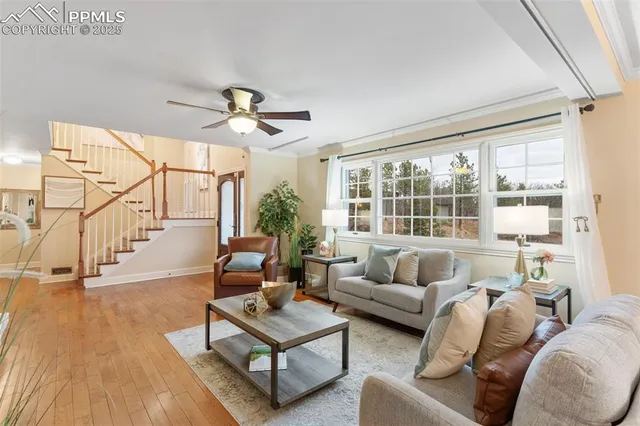 a living room with furniture a ceiling fan and a large window