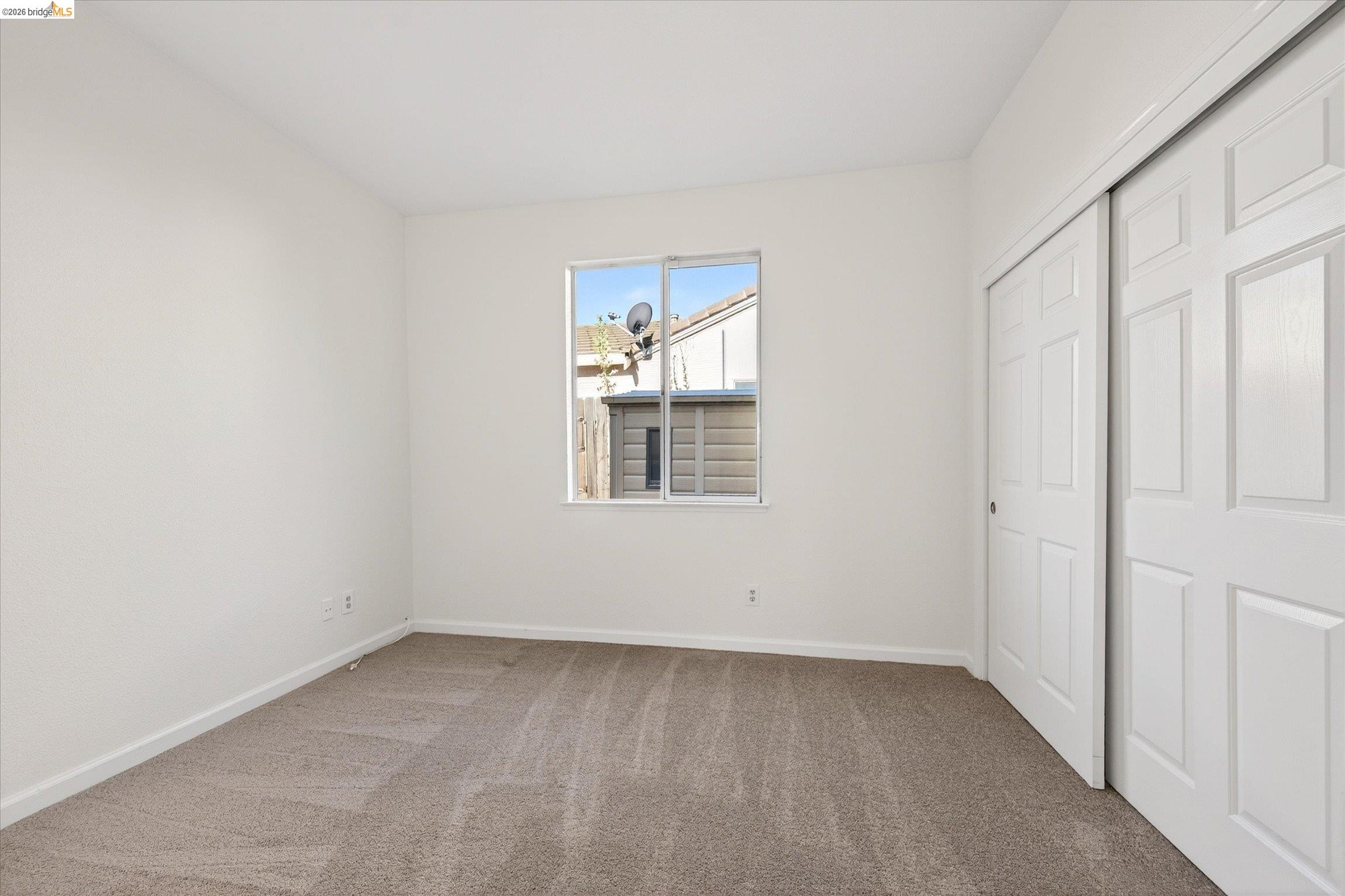 1120 Deerpark Road Oakley, CA 94561 - Photo 17 of 30 Neutral paint palette bedroom with a double-pane window, light brown carpet, and white bi-fold closet doors