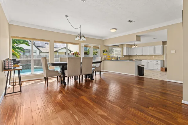 a view of a dining room and livingroom with furniture wooden floor a chandelier