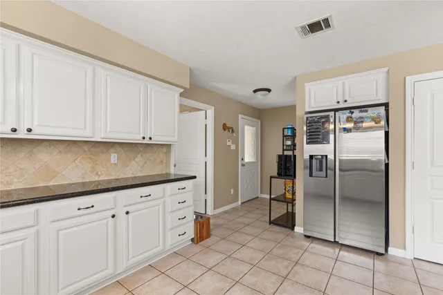 a kitchen with granite countertop a refrigerator and white cabinets