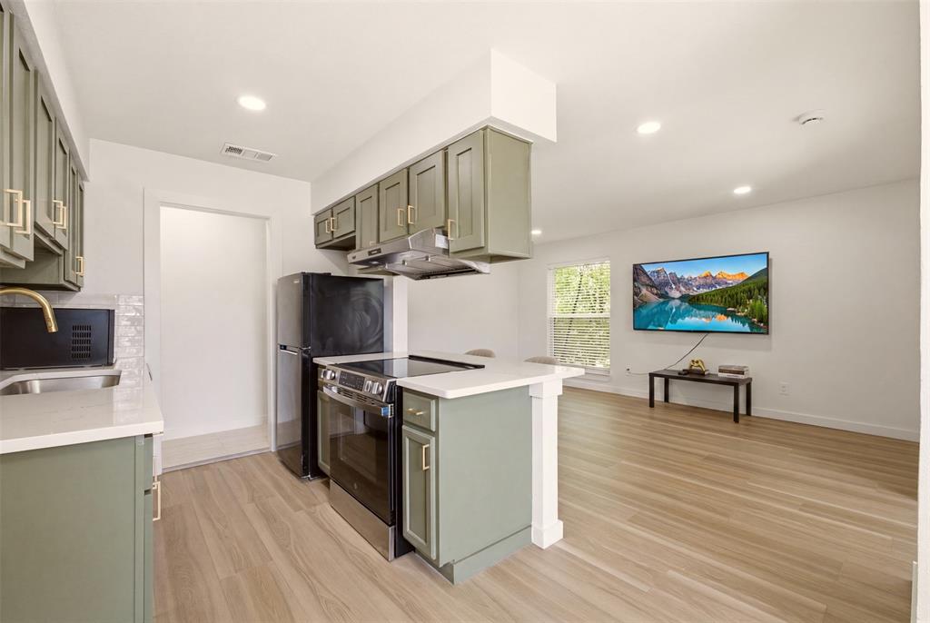 908 Isbell Road, Unit D Fort Worth, TX 76114 - Photo 5 of 27 Open-concept kitchen and living area featuring sage green cabinetry, recessed lighting, and wood-finish flooring