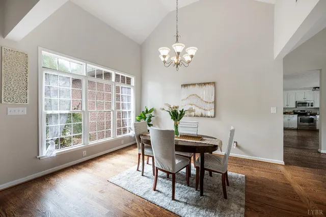a dining room with wooden floor a chandelier a glass table and chairs
