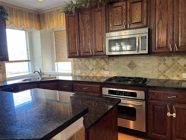 a kitchen with granite countertop a stove a sink and a microwave
