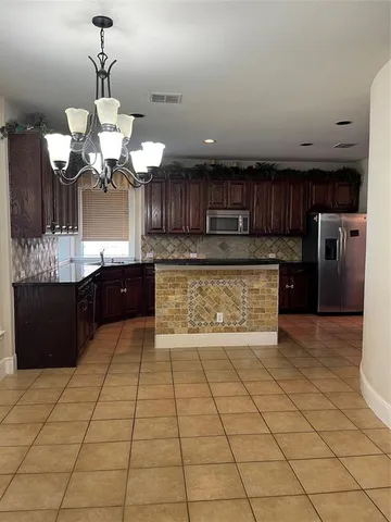 a large kitchen with stainless steel appliances granite countertop a stove a sink and a microwave