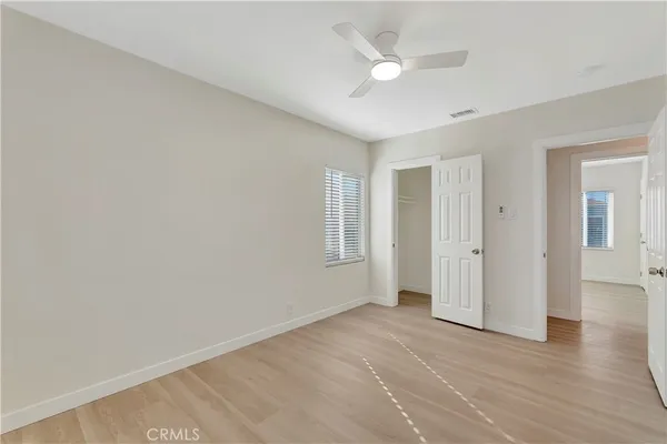 an empty room with wooden floor and ceiling fan