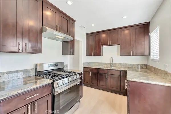 a kitchen with stainless steel appliances granite countertop a stove a sink and a microwave