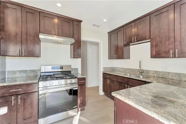 a kitchen with granite countertop a sink stove and refrigerator