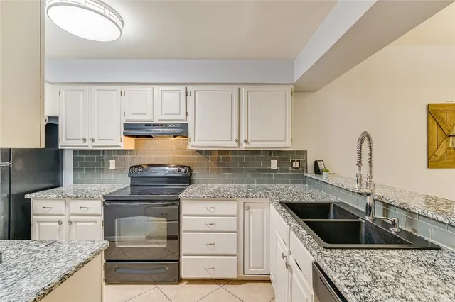 a kitchen with kitchen island granite countertop a sink stove and cabinets