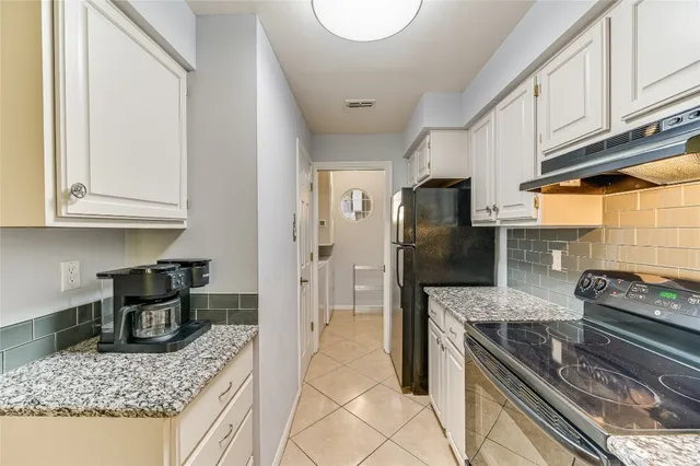 a kitchen with stainless steel appliances granite countertop a sink a stove a refrigerator cabinets and chairs