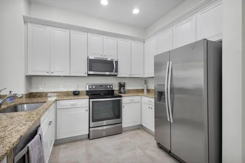 a kitchen with stainless steel appliances granite countertop a refrigerator stove and sink