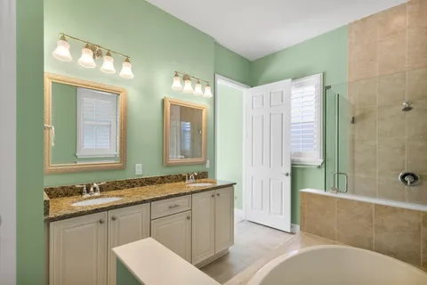 a bathroom with a granite countertop tub double vanity sink and a mirror