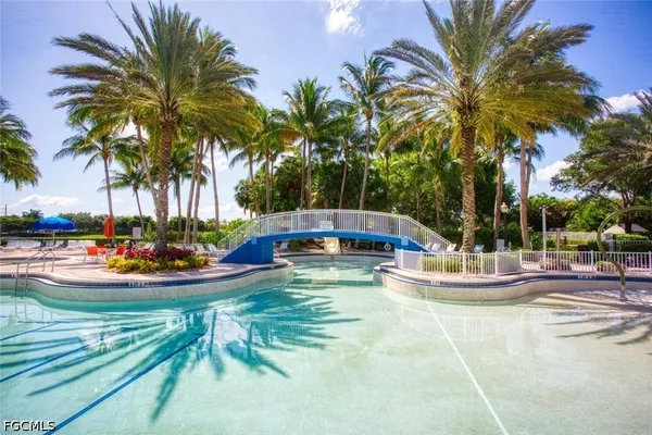 a view of a swimming pool with a lawn chairs under palm trees