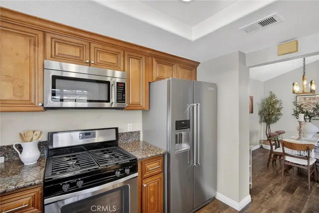 a kitchen with stainless steel appliances granite countertop a stove refrigerator and microwave