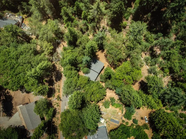 an aerial view of residential house with outdoor space and trees all around