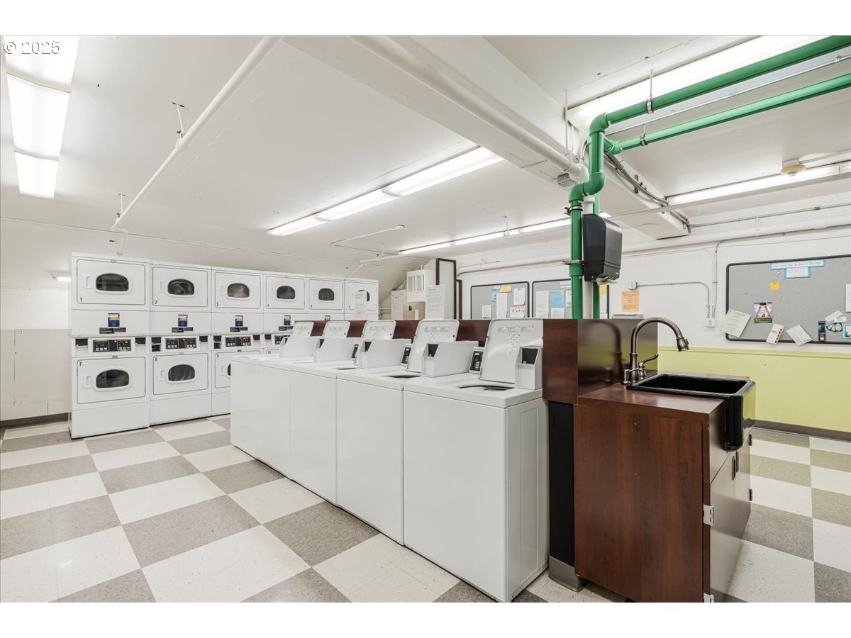 255 Southwest Harrison Street, Unit 11A Portland, OR 97201 - Photo 25 of 32 a kitchen with stainless steel appliances kitchen island a refrigerator sink and white cabinets with wooden floor