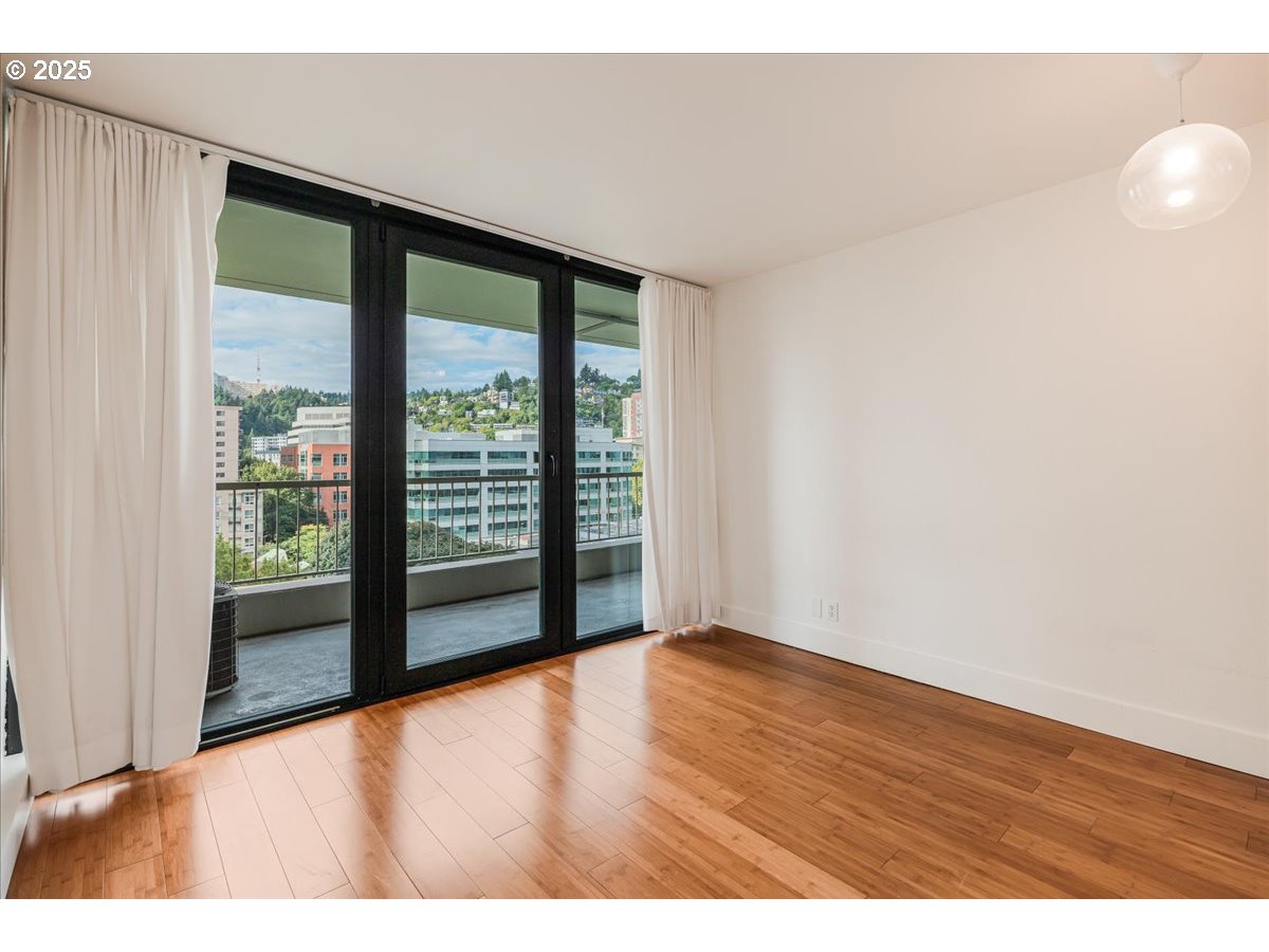 255 Southwest Harrison Street, Unit 11A Portland, OR 97201 - Photo 3 of 32 a view of an empty room with wooden floor and a window