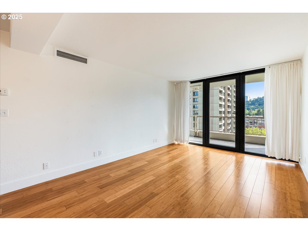 255 Southwest Harrison Street, Unit 11A Portland, OR 97201 - Photo 4 of 32 a view of an empty room with wooden floor and a window