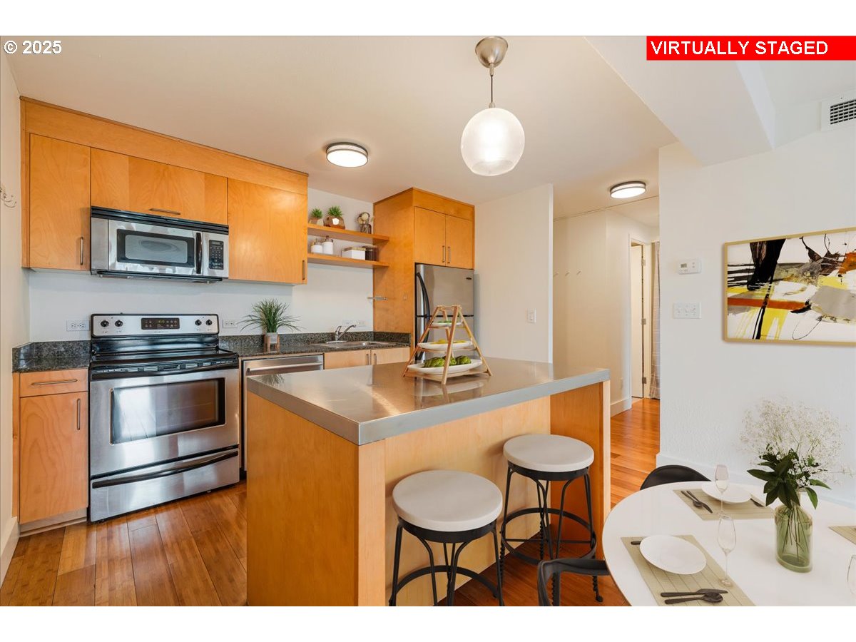 255 Southwest Harrison Street, Unit 11A Portland, OR 97201 - Photo 10 of 32 a kitchen with stainless steel appliances a stove a sink cabinets and a dining table