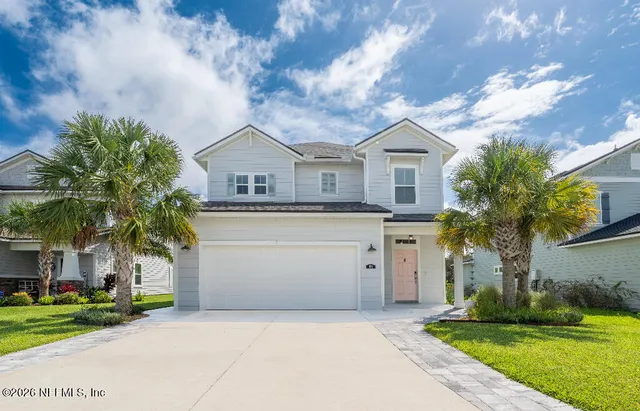 a front view of a house with a garden and trees